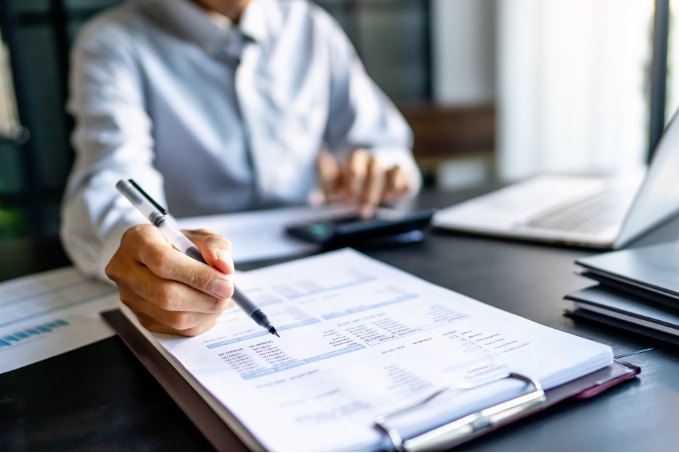 Businessperson gesturing with a pen at a paper on a clipboard